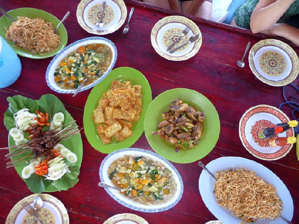 Indonesische rijsttafel met saté, noedels en groenten op tafel tijdens Familiereis Kleine Sunda Eilanden.