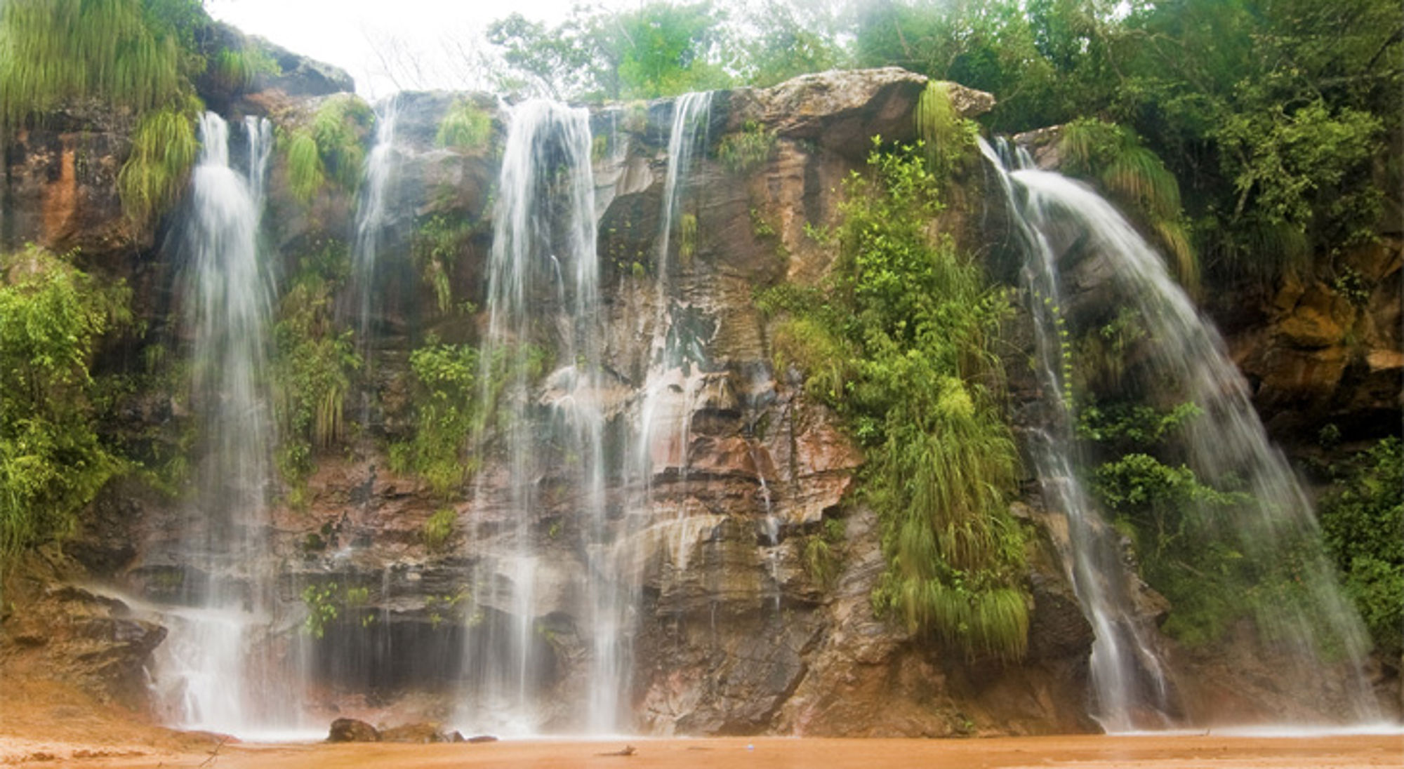 Waterval die over een rotswand stroomt, omringd door groen in Bolivia.