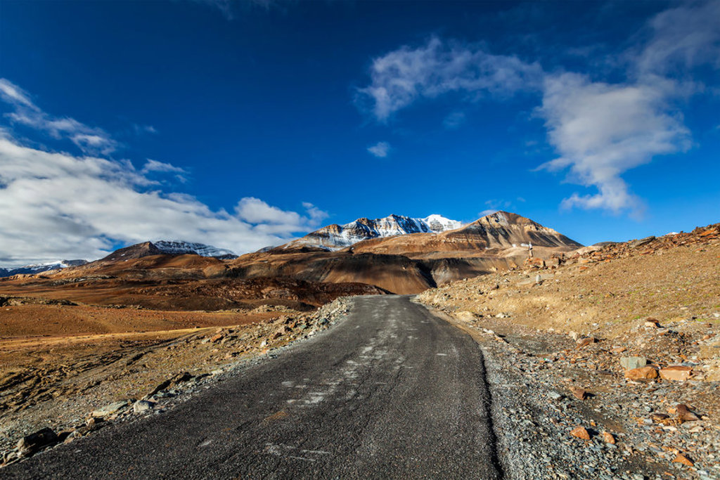 Weg door het berglandschap van Ladakh in India, met besneeuwde toppen onder een blauwe lucht.