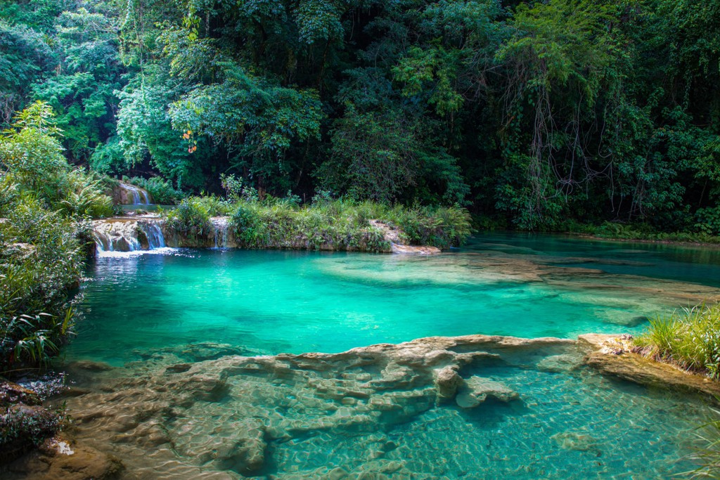 Turquoise waterval en natuurlijke zwempoel in het regenwoud tijdens 22-35ers reis Guatemala, Honduras en El Salvador.