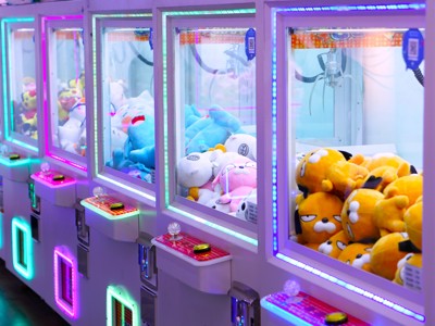Neonverlichte Japanse grijpmachines met knuffels in een arcadehal, onderdeel van Route Japan.