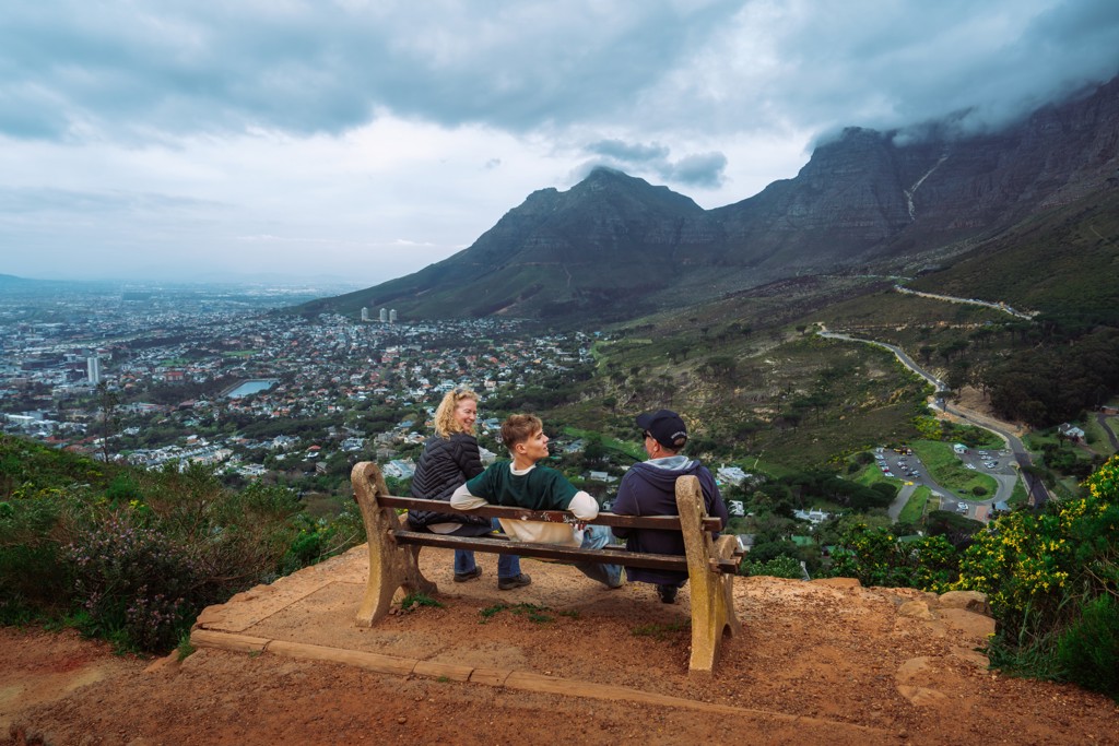 Gezin op een bankje met uitzicht over Kaapstad en de Tafelberg tijdens een familiereis Zuid-Afrika en eSwatini.