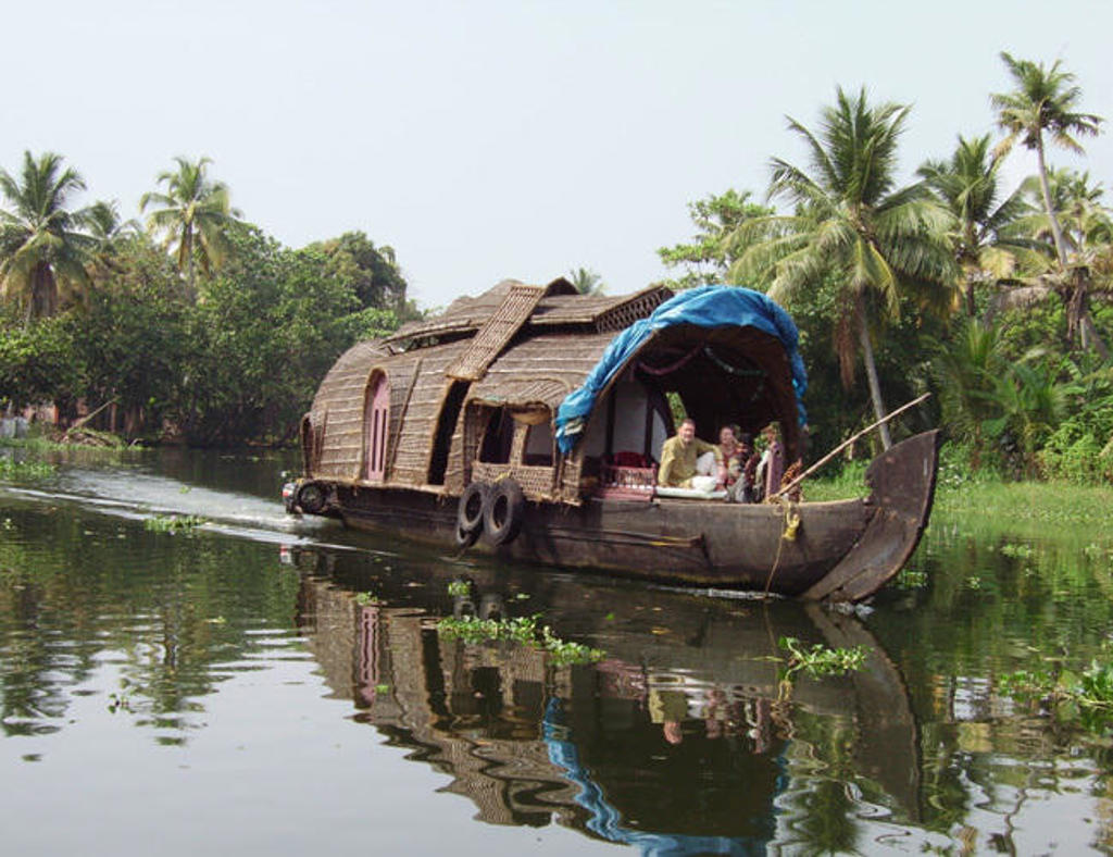 Traditionele houseboat op de backwaters van Zuid-India, omringd door palmbomen.
