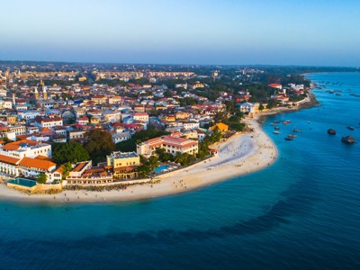 Stone Town in Zanzibar met wit zandstrand en traditionele boten langs de kust.