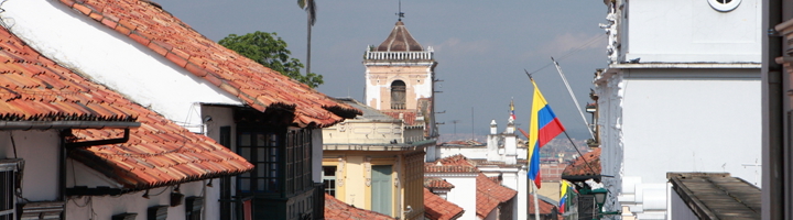 Straatbeeld in La Candelaria, Bogotá met kleurrijke huizen, kerktoren en Colombiaanse vlag.