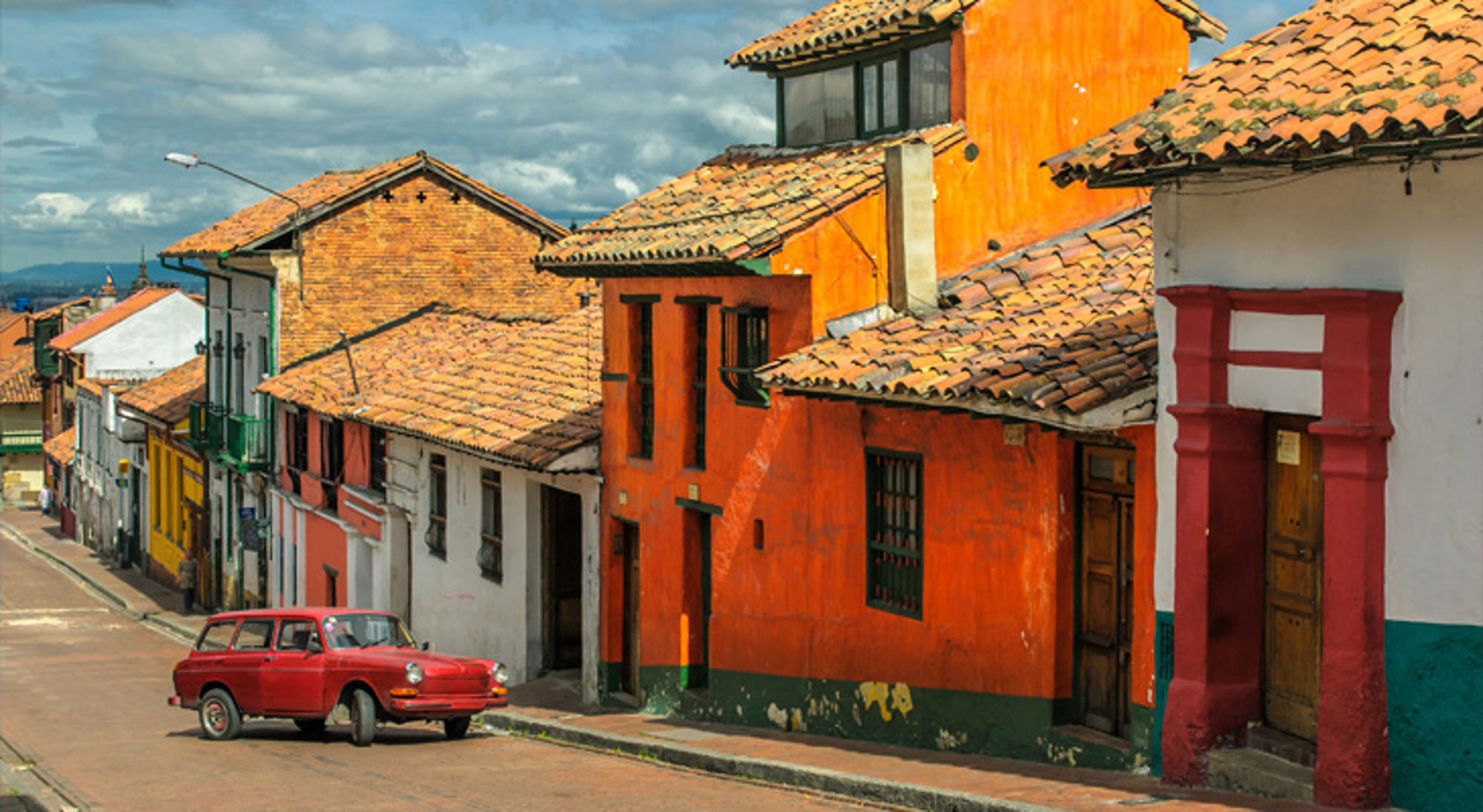 Gekleurde straat met traditionele huizen en rode auto in Colombia.
