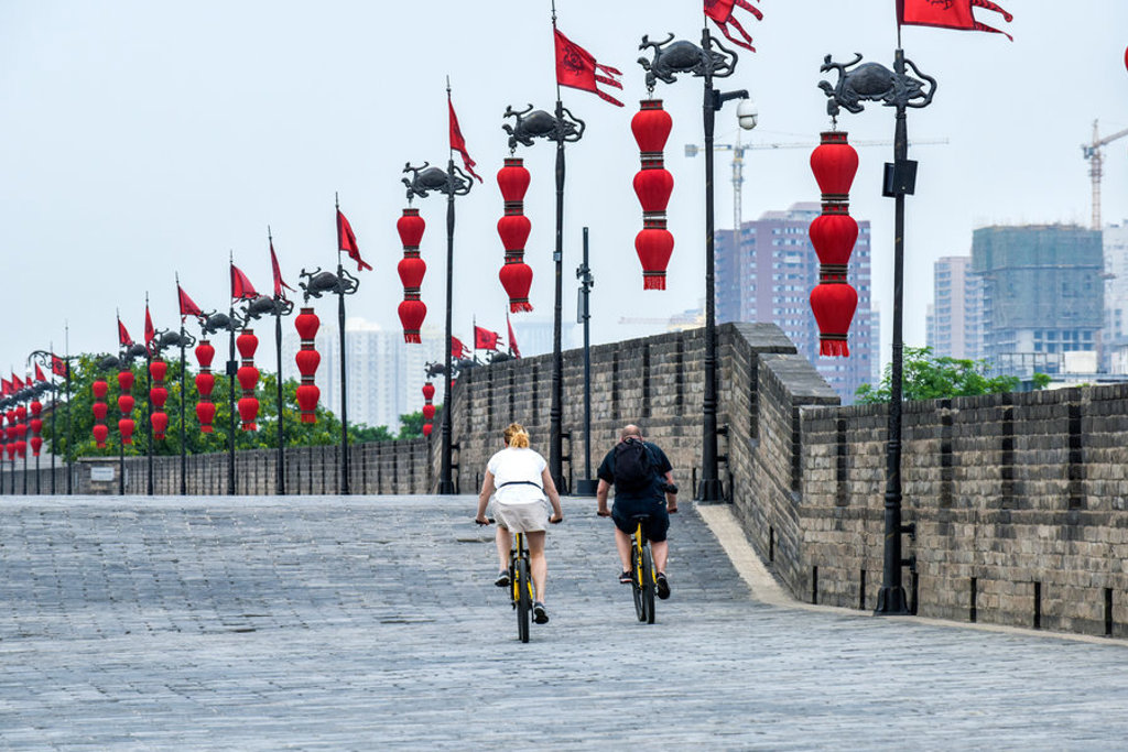 Fietsers op de stadsmuur van Xi’an met rode Chinese lantaarns tijdens een groepsrondreis China.