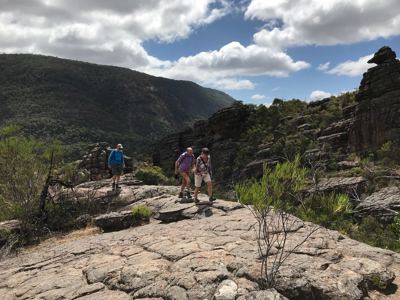 Wandelaars op rotsplateau in de Grampians, Australië, met uitzicht op bergen en wolkenlucht.