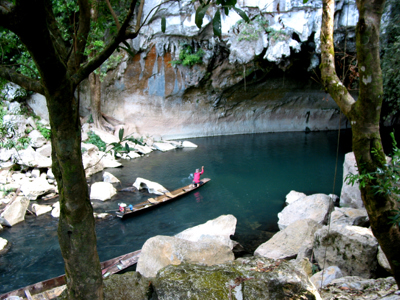 Boottocht over een smalle rivier langs kalkstenen rotswanden tijdens de route Laos & Cambodja.