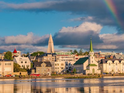 Reykjavik met Hallgrímskirkja en kerk aan het water, met regenboog boven de stad.