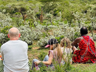 Safariwandelaars spotten giraffen in de savanne tijdens de route Kenia, Tanzania en Zanzibar.