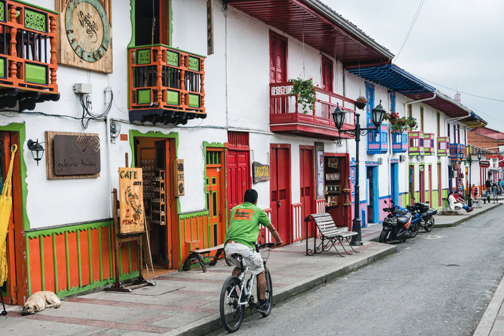 Kleurrijke straat met koloniale balkons en fietser in Colombia tijdens een familiereis.