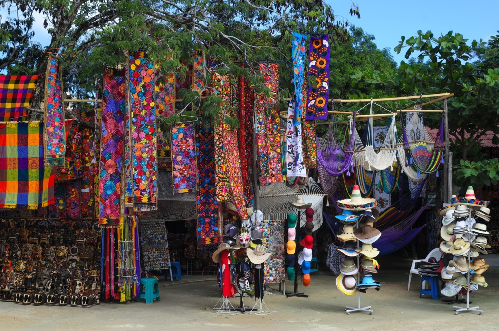 Kleurrijke Mexicaanse markt met geborduurde doeken, hangmatten en hoeden tijdens een familiereis langs hoogtepunten in Mexico.