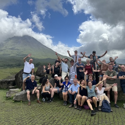 Groepsrondreis Costa Rica: reizigers poseren bij de Arenal-vulkaan, met groene hellingen en wolkenlucht.