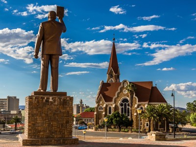 Standbeeld voor de Christuskirche in Windhoek, Namibië, onder een blauwe lucht met wolken.