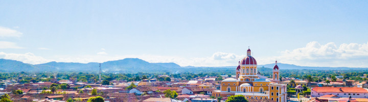 Uitzicht op de kathedraal van Granada in Nicaragua, met kleurrijke daken en bergen op de achtergrond.