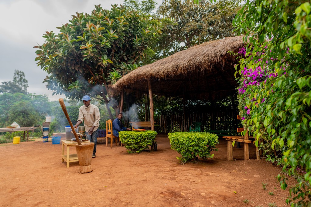 Buitenkeuken bij lodge tijdens 22-35ers reis Kenia & Tanzania, met kok bij vuur naast rieten overkapping.