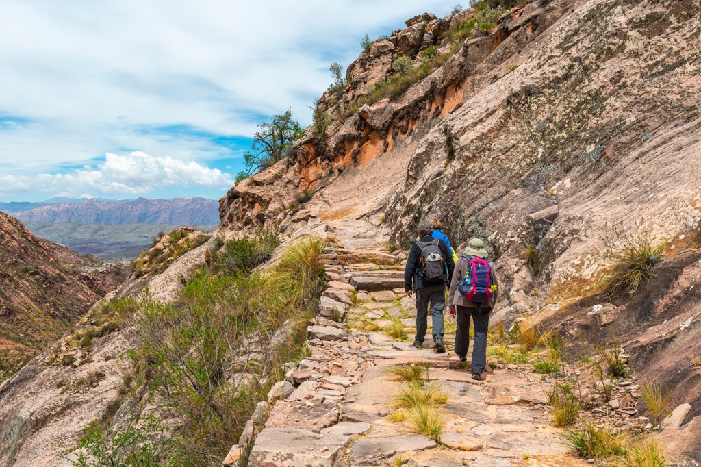 Wandelaars op een bergpad langs rotsen in Peru tijdens een groepsrondreis.