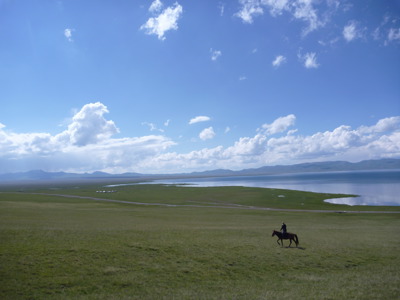Ruiter te paard in de Mongoolse steppe bij een groot meer, Route Zijderoute.