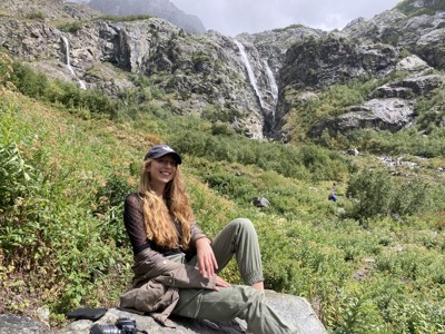 Wandelaar in de bergen van Georgië met waterval op de achtergrond.