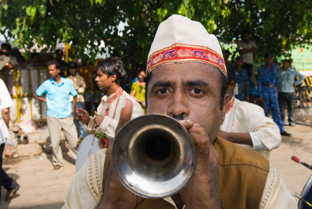 Muzikant speelt trompet tijdens straatfeest in Noord-India.