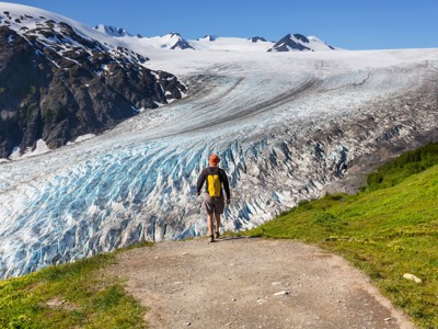 Wandelaar kijkt uit over een enorme gletsjer in Alaska tijdens de Route Alaska.