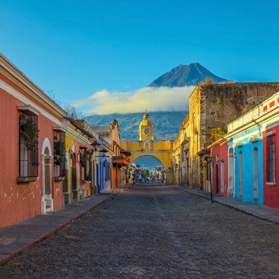 Kleurrijke straat in Antigua Guatemala met de Santa Catalina-boog en de Agua-vulkaan op de achtergrond.