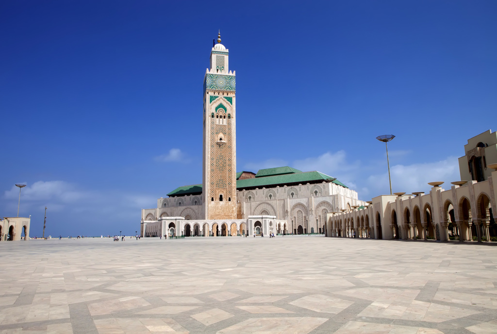 Hassan II-moskee in Casablanca, Marokko, met hoge minaret en groot plein onder een blauwe lucht.
