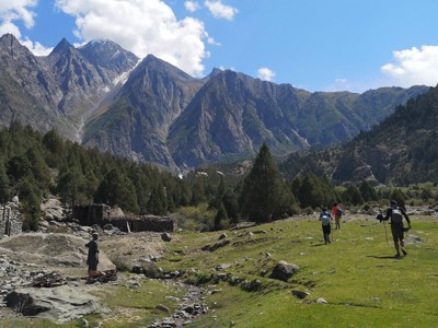 Wandelaars in een groene vallei met hoge bergtoppen in Baltistan, Pakistan.