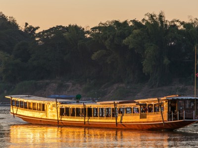 Traditionele houten rivierboot bij zonsondergang op de Mekong, route Indochina.