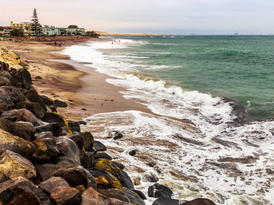 Kustlijn bij Swakopmund met rotsen, zandstrand en golven aan de Atlantische Oceaan.