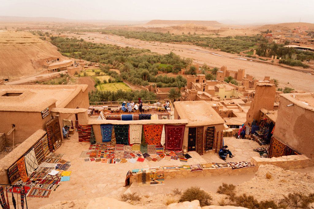 Uitzicht over Aït Ben Haddou met kleurrijke tapijten en de oasevallei tijdens een 22-35ers reis Marokko.
