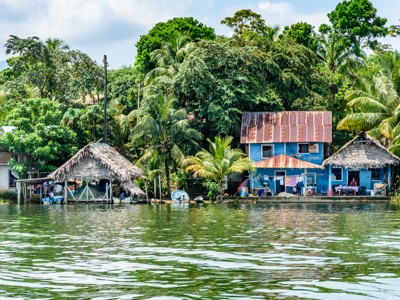 Huizen aan de oever van Río Dulce, Guatemala, omringd door tropisch groen.