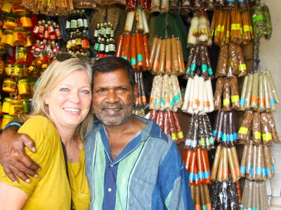 Reizigers poseren bij een kruidenkraam in Sri Lanka met kleurrijke specerijen op de achtergrond.