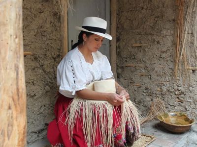 Ecuadoraanse vrouw in traditionele kleding vlecht stro tot handwerk tijdens rondreis Ecuador en Galapagos.