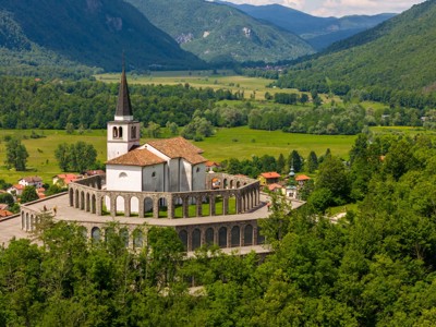 Bedevaartskerk Sveta Gora boven de Soča-vallei in Slovenië, met uitzicht op groene bergen.