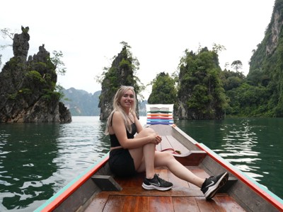 Jonge reiziger in longtailboot op het Cheow Lan-meer in Khao Sok, omringd door kalksteenrotsen.