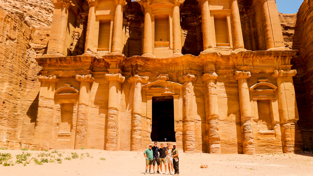 Groep reizigers bij het rotsgraf Ad Deir in Petra, Jordanië.