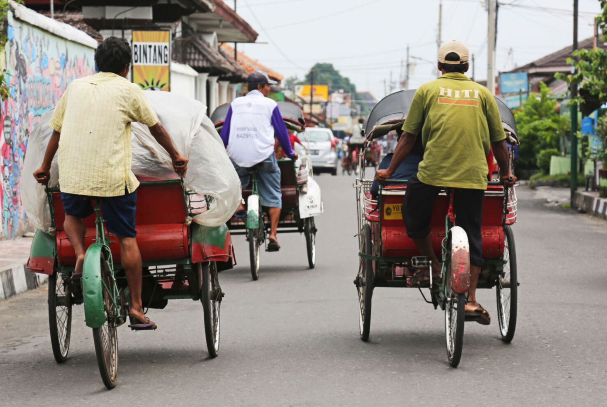 Fietstaxi’s (becaks) rijden door een drukke straat in Indonesië.