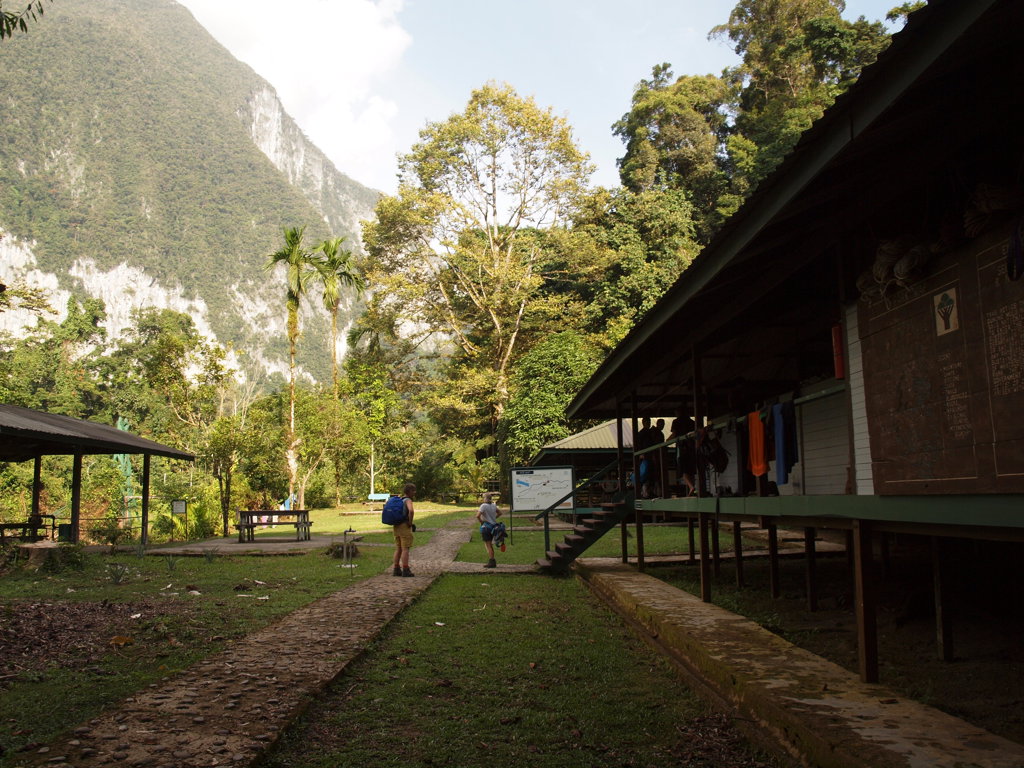 Wandelaars bij een jungle lodge in Maleisisch Borneo, met kalkstenen bergwand op de achtergrond.