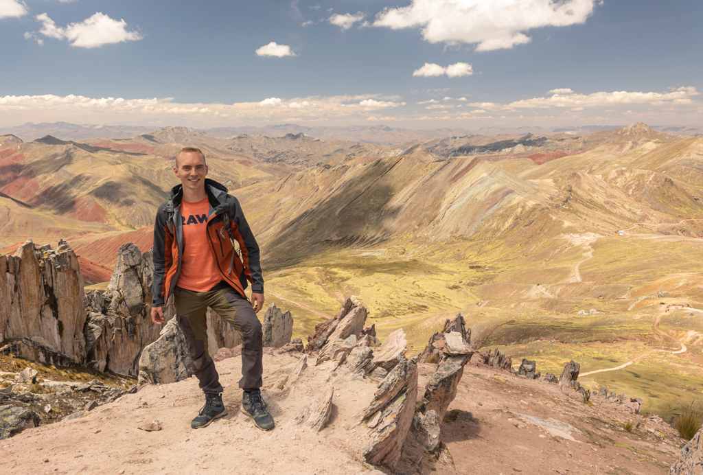 22-35ers reiziger bij Rainbow Mountain met uitzicht op kleurrijke Andesbergen in Peru.