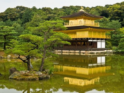 Gouden Kinkaku-ji tempel in Kyoto met weerspiegeling in de vijver, omringd door groene bomen.