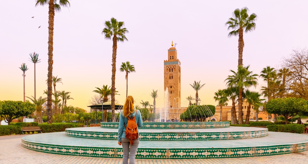 Reiziger bij fontein met de Koutoubia-moskee op de achtergrond in Marrakech, tijdens familiereis Marokko Hoogtepunten.