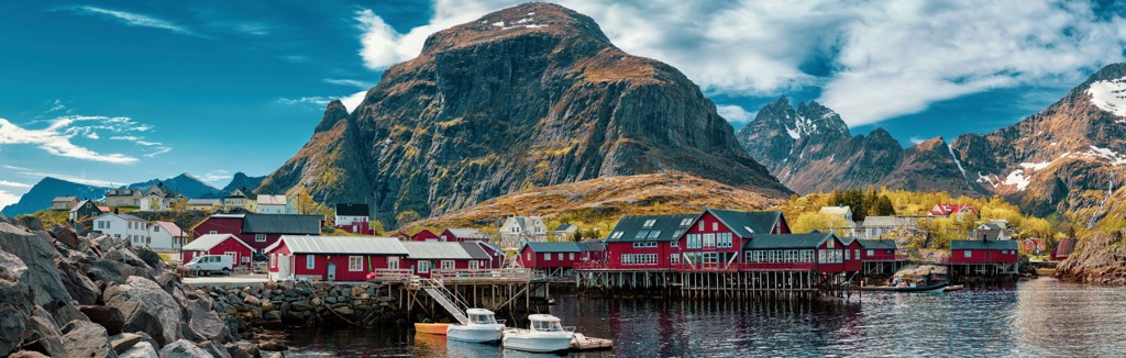 Rode vissershuisjes aan een fjord met bergen op de achtergrond in Noorwegen.
