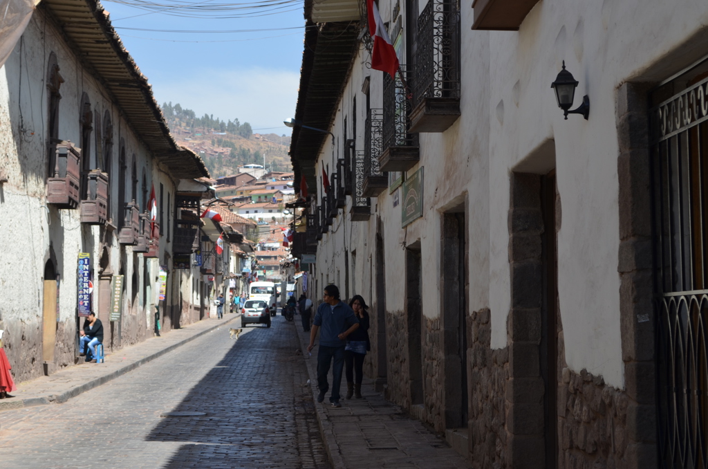 Straat met koloniale gebouwen en Peruaanse vlaggen in Cusco, Peru, tijdens een familiereis.