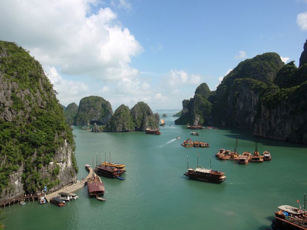 Uitzicht over Halong Bay in Vietnam met kalkstenen rotsen en traditionele boten op turquoise water.