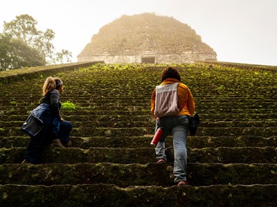 Twee reizigers beklimmen de trappen van een Maya-tempel in Guatemala en Belize.