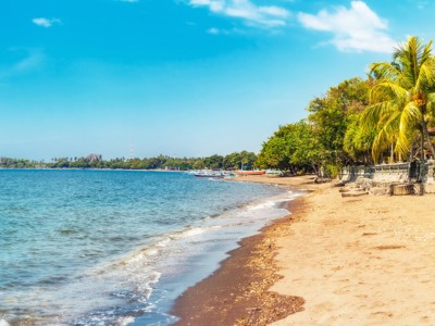 Rustig zandstrand met palmbomen en kalme zee tijdens de Route Java en Bali.