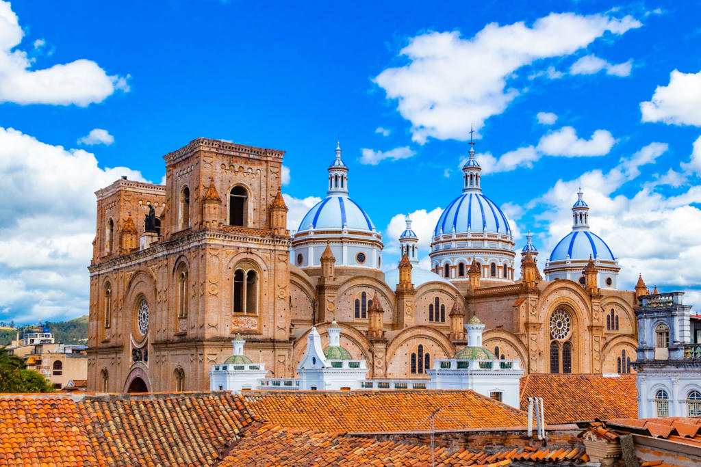 Kathedraal van Cuenca met blauw-witte koepels en oranje dakpannen onder een heldere lucht in Ecuador.