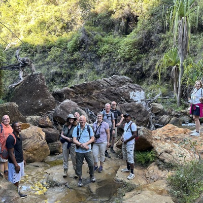 Groep wandelaars tijdens een groepsrondreis Madagascar in een groene kloof met rotsen en een beekje.